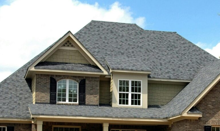 Classic two-story brick house with gable roof and front lawn in suburban setting.